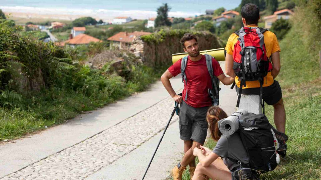 Tres peregrinos descansando y hablando en un camino de una aldea